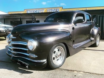  Classic black Chevrolet hot rod parked outside tyre shop