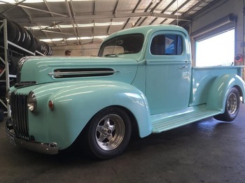  Light blue classic Ford F100 hot rod pickup inside tyre workshop