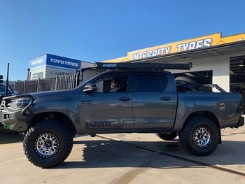  Grey Toyota Hilux dual cab lifted with aggressive off-road tyres outside tyre shop