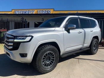  White Toyota LandCruiser 300 Series with off-road tyres parked outside a tyre shop