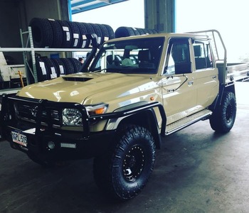  Beige Toyota LandCruiser 79 Series dual cab with tray back and off-road tyres inside workshop
